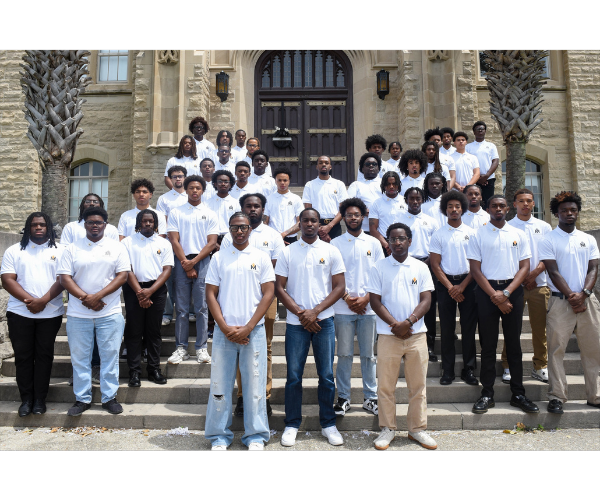 Men of Xavier administration standing on a staircase in the shape of an "X" in white polo shirts