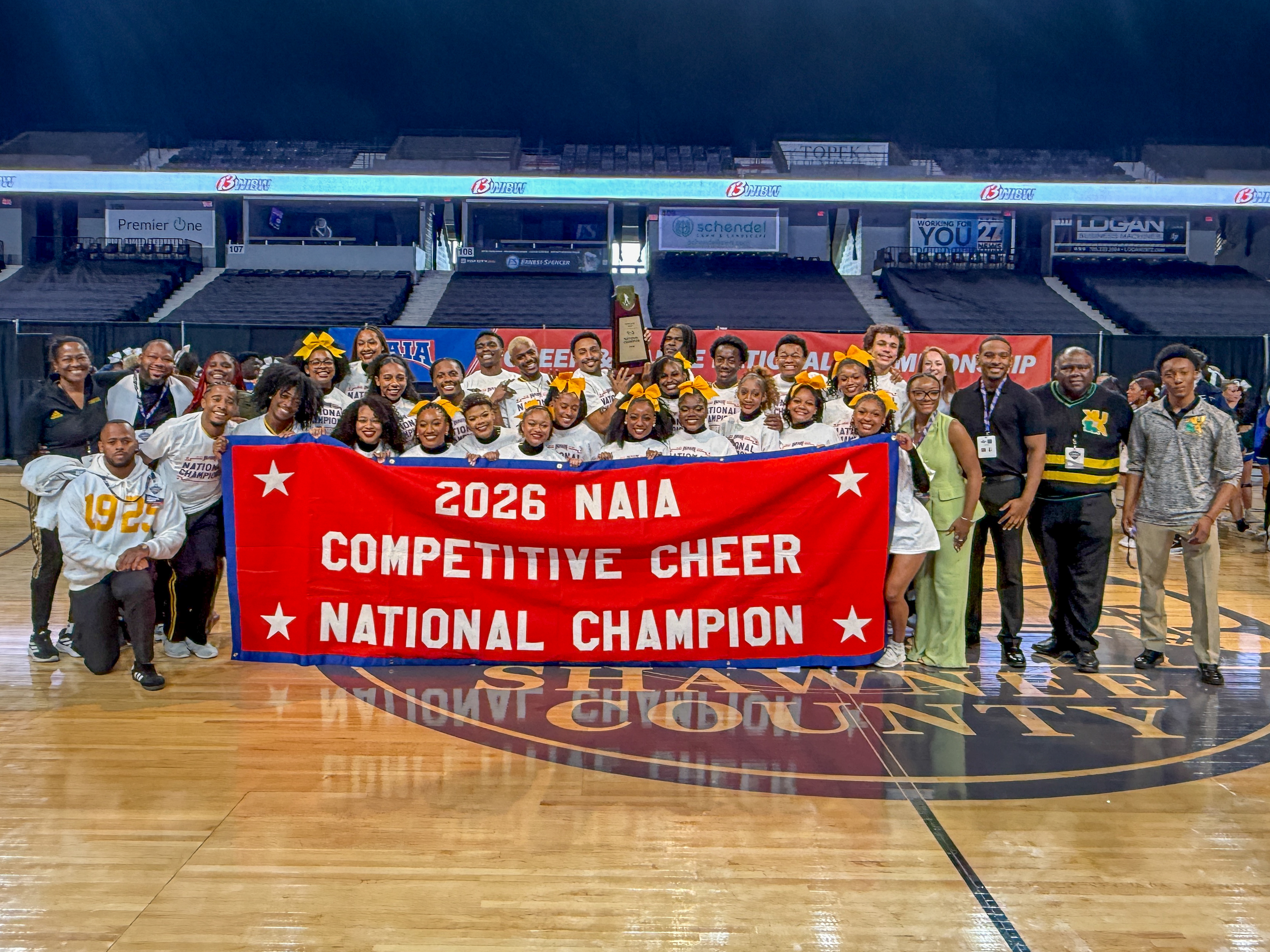 Xavier University of Louisiana cheer team, coaches holding up banner that reads "2026 NAIA Competitive Cheer National Champion"