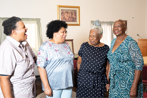 Four women standing next to each other and laughing