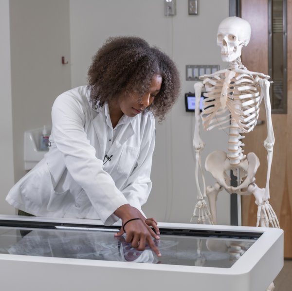 Student in lab coat with model skeleton